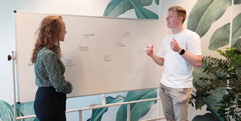 Jolien en Sytse staan in gesprek  voor een whiteboard met aantekeningen over storytelling